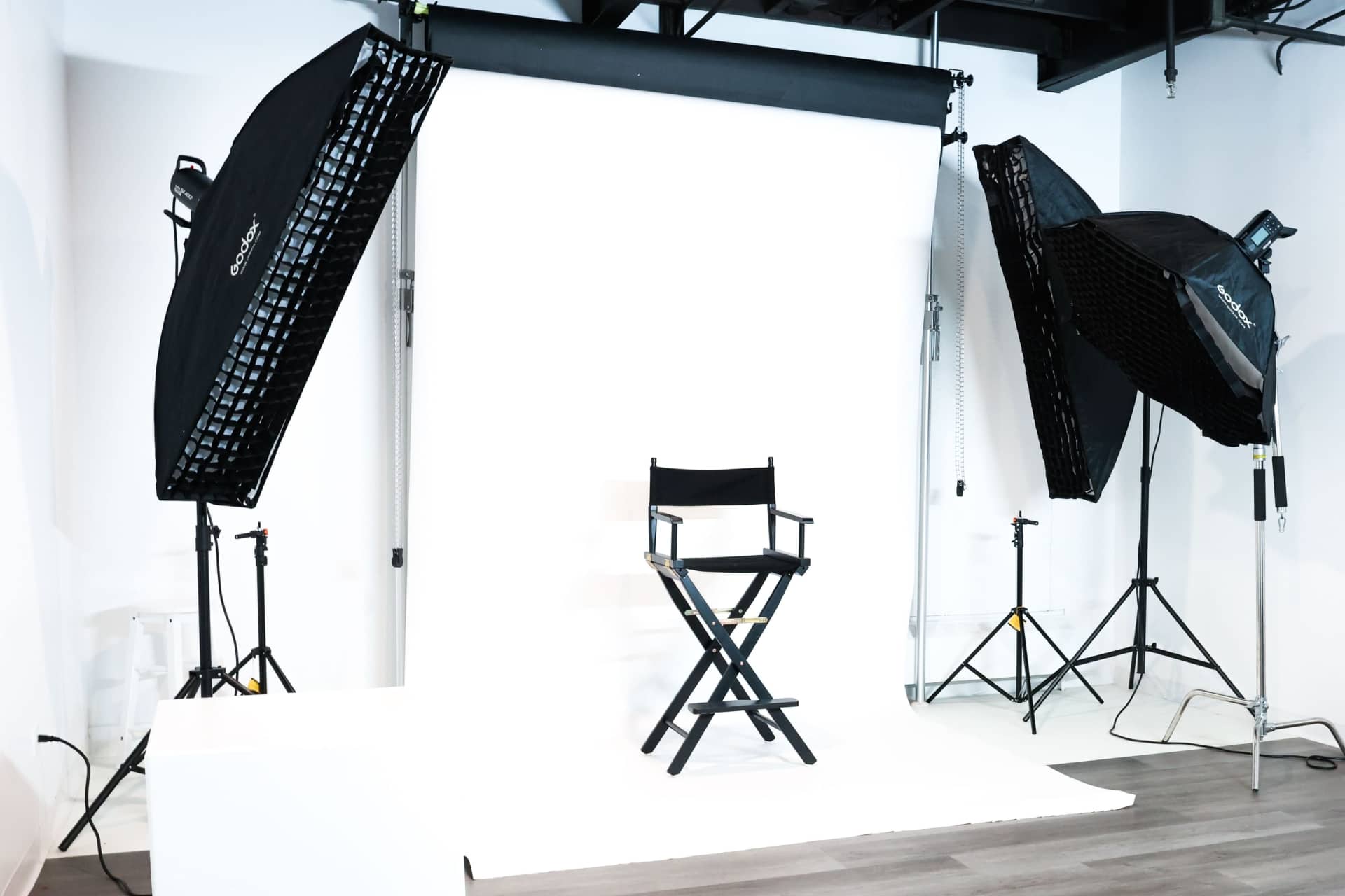 Photo studio with a white backdrop, chair, and softbox lights